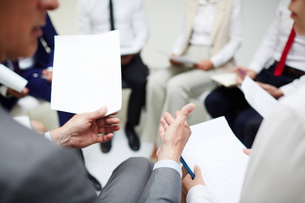People holding documents and having a discussion.